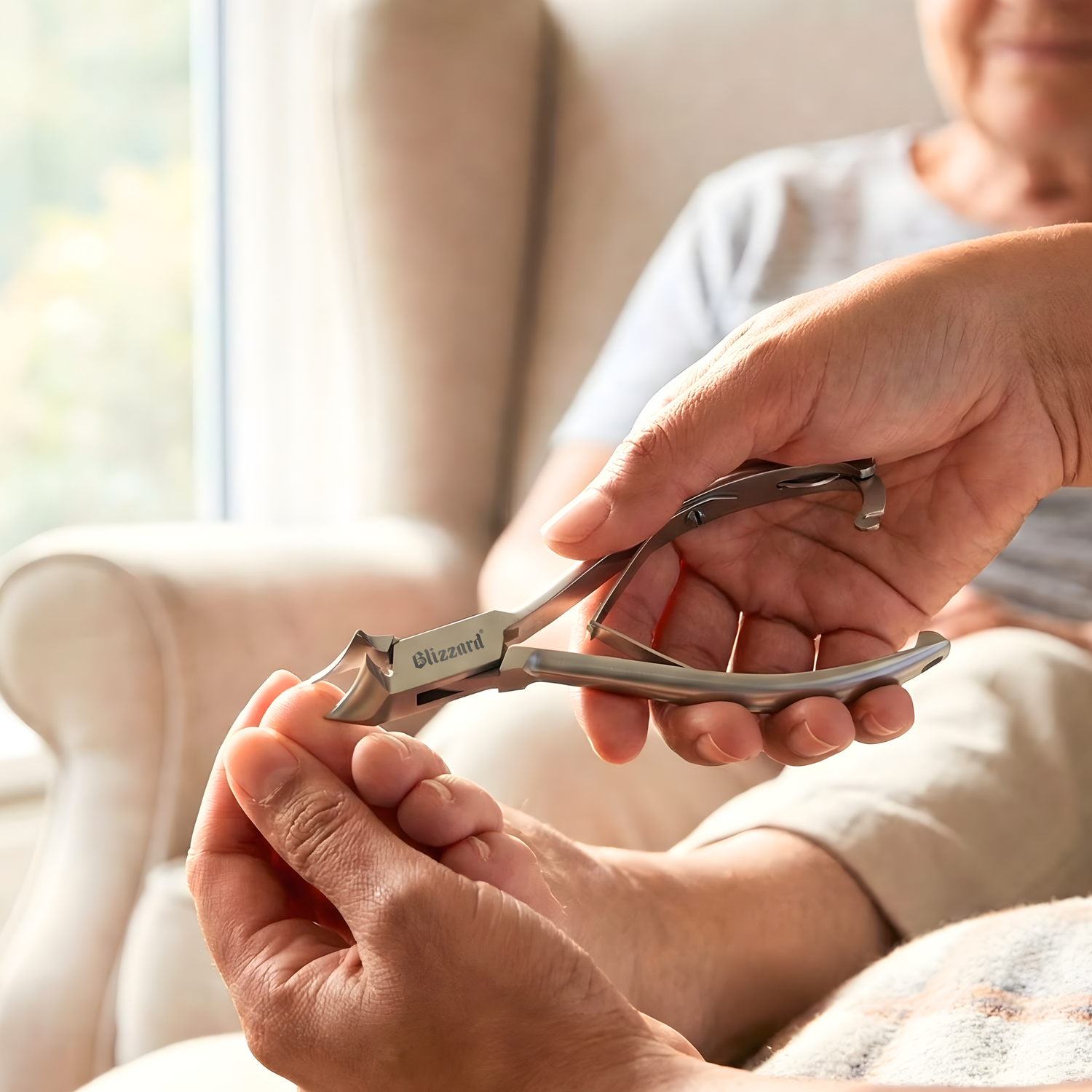 Person using a nail clipper on another person's foot with a blurred background